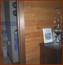 Close-up of the varnished knotty pine panelling & mahoganogy trim, at the entrance to the  main floor 2-peice bathroom.